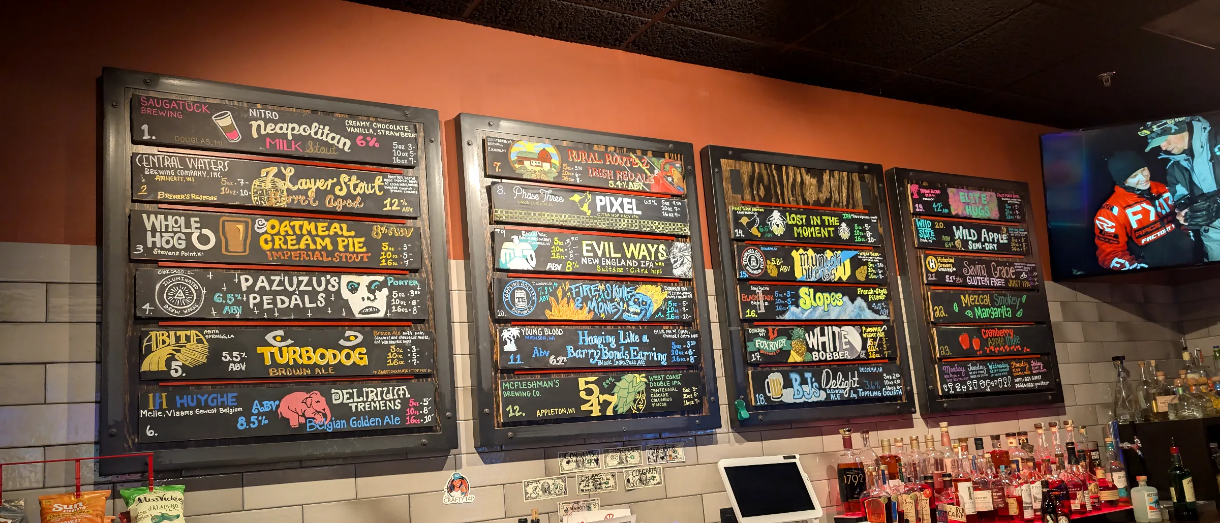 Four black-framed boards of hand-painted tap names over the back bar