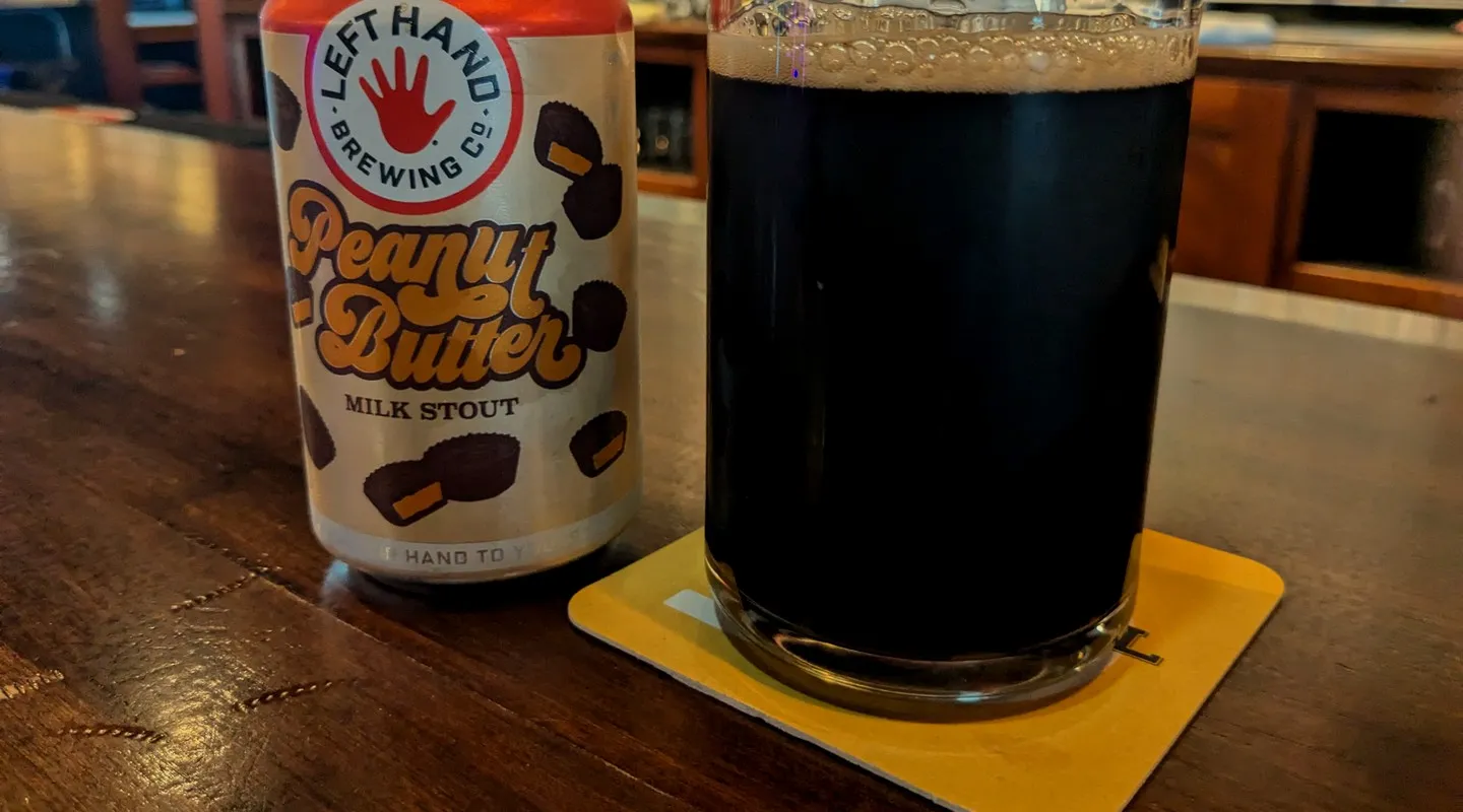 A milk stout can and a poured stout on a coaster at the bar
